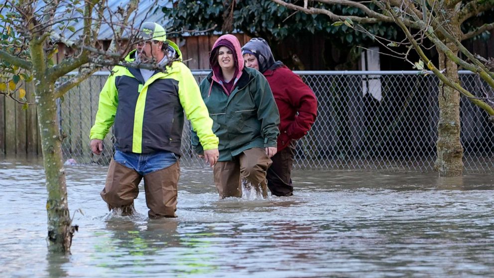 PHOTO: Dale Archer, left, leads his daughters Myranda and Krysten Archer through floodwater, Nov. 15, 2021, in Sedro-Woolley, Wash., after heavy rainfall brought major flooding of the Skagit River.