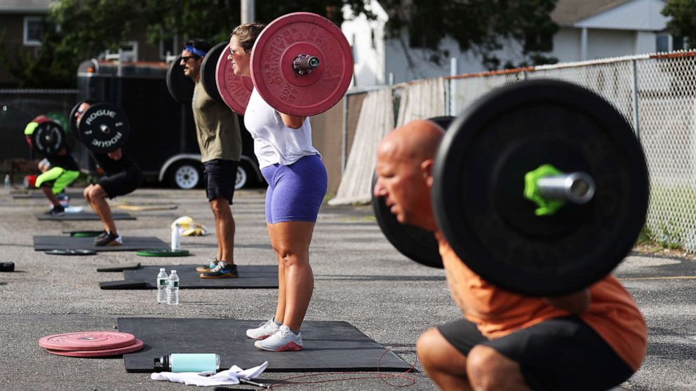 PHOTO: Taylor Wroblewski and her Dad Frank squat during an outdoor Jetty Gym "Outside The Box" fitness workout, July 20, 2020, in Oceanside, New York.