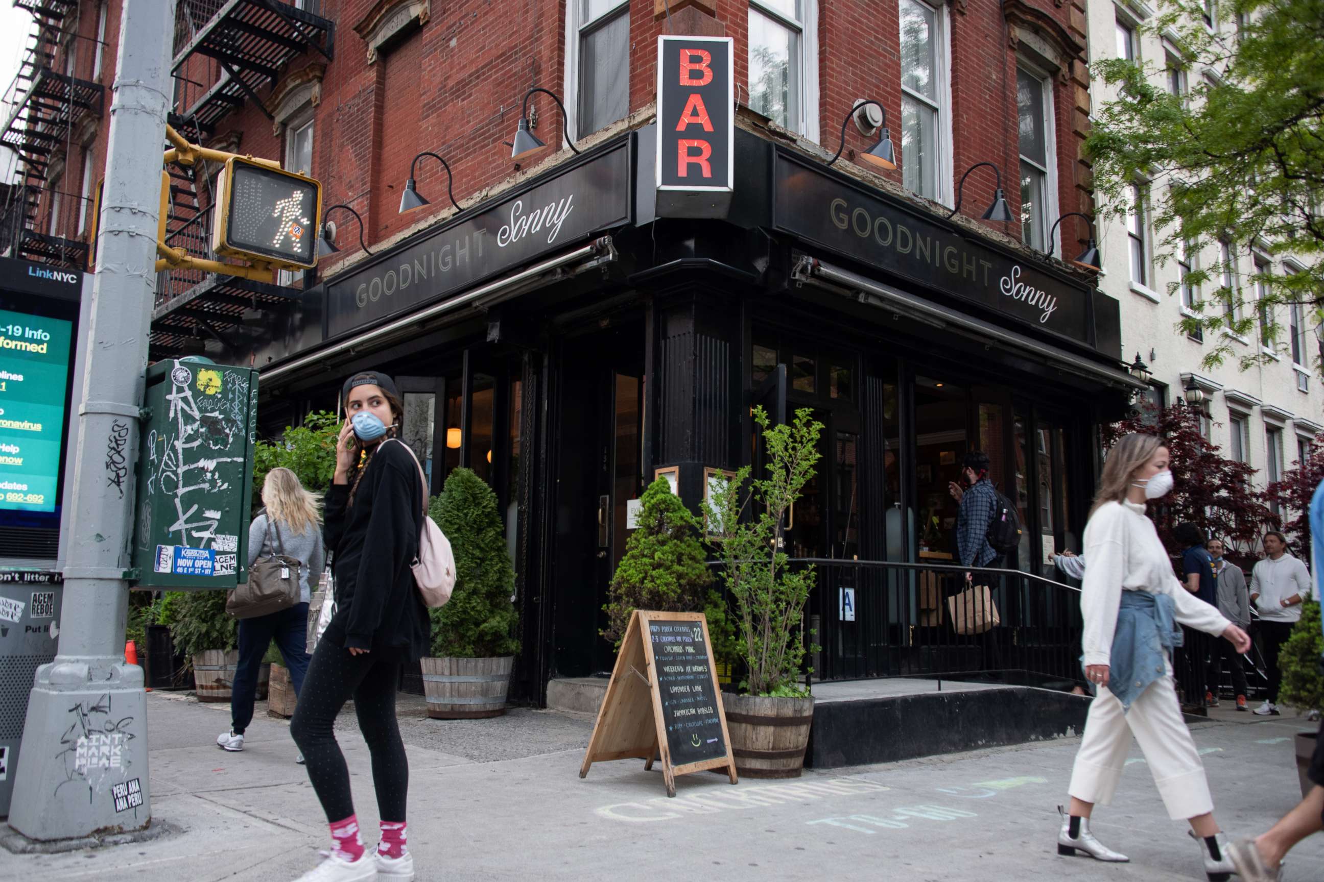 PHOTO: People wearing masks walk past an recently reopened bar in the East Village amid the coronavirus pandemic, May 14, 2020, in New York City.