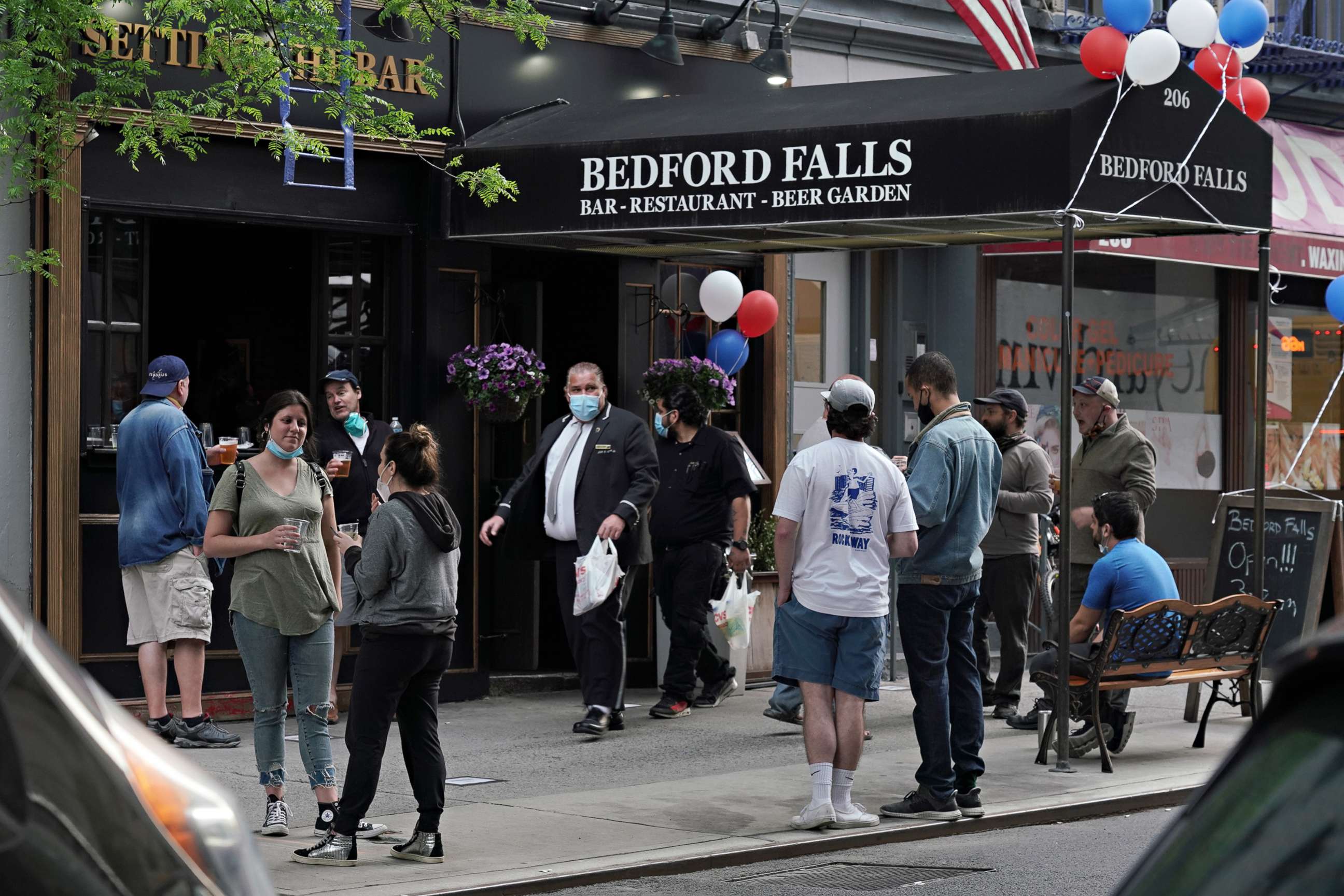 PHOTO: People gather outside a bar selling to-go drinks during the coronavirus pandemic on May 18, 2020 in New York City.