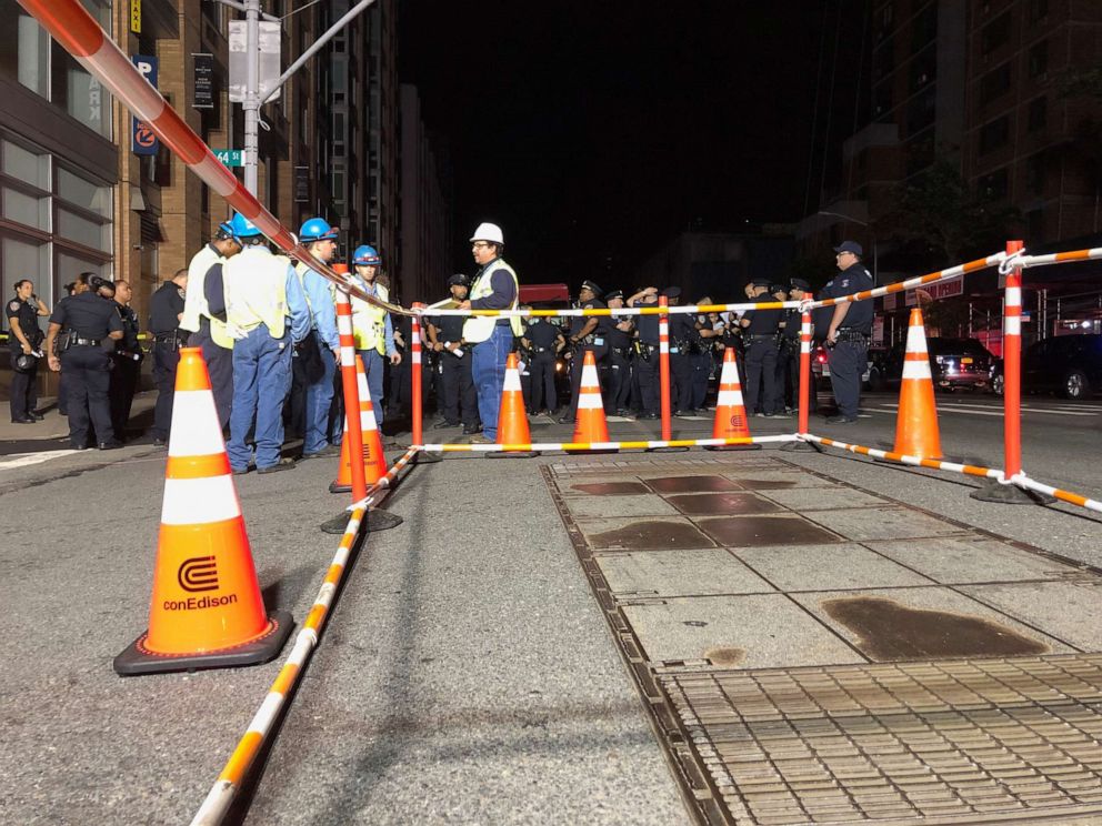 PHOTO: Con Edison workers stand around a barricaded transformer cover as a blackout affects buildings and traffic during widespread power outages in the Manhattan borough of New York, July 13, 2019.