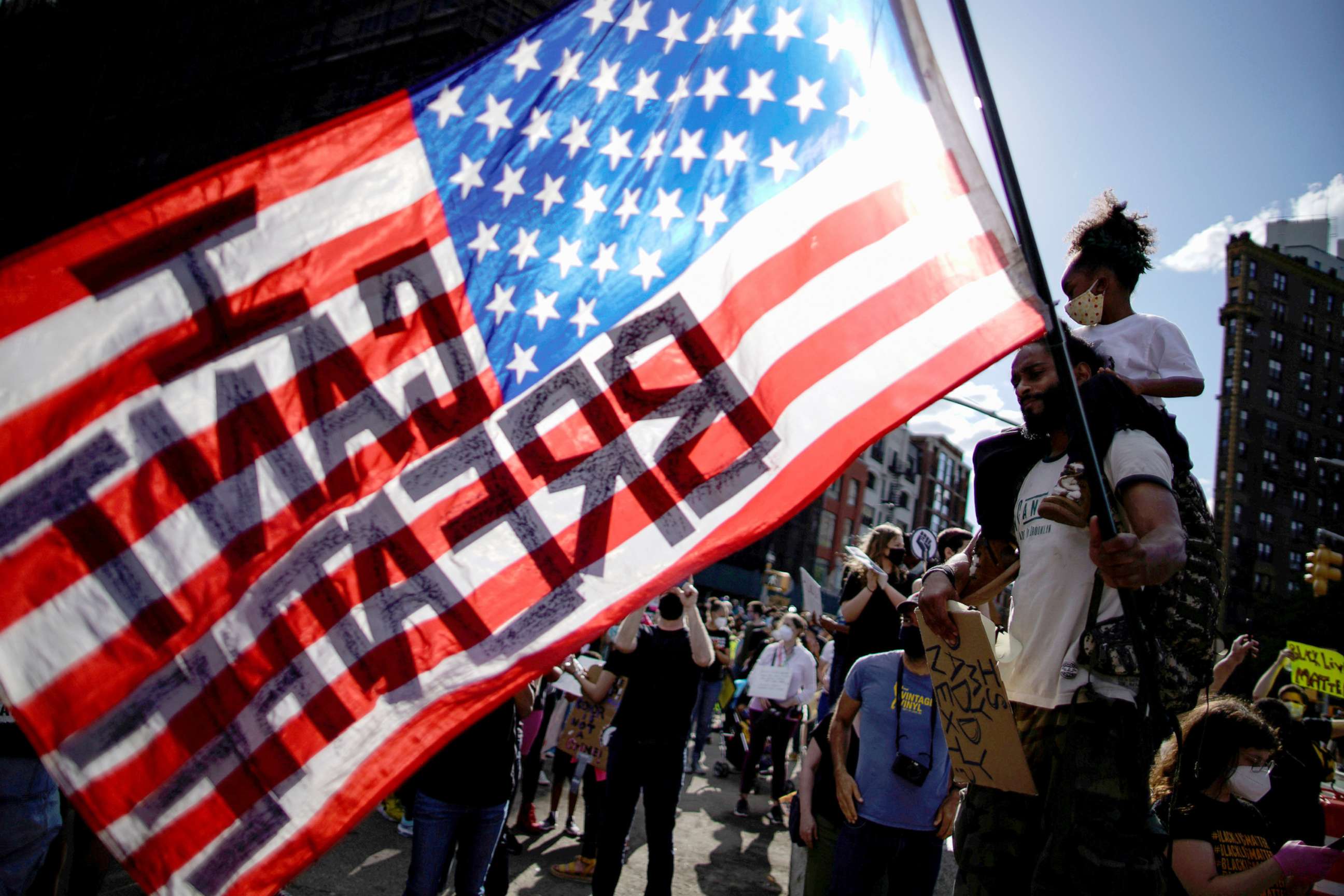 PHOTO: A child sits on her father's shoulders as he carries a U.S. flag during a protest against racial inequality in the aftermath of the death in Minneapolis police custody of George Floyd, in the Brooklyn borough of New York City, June 7, 2020.