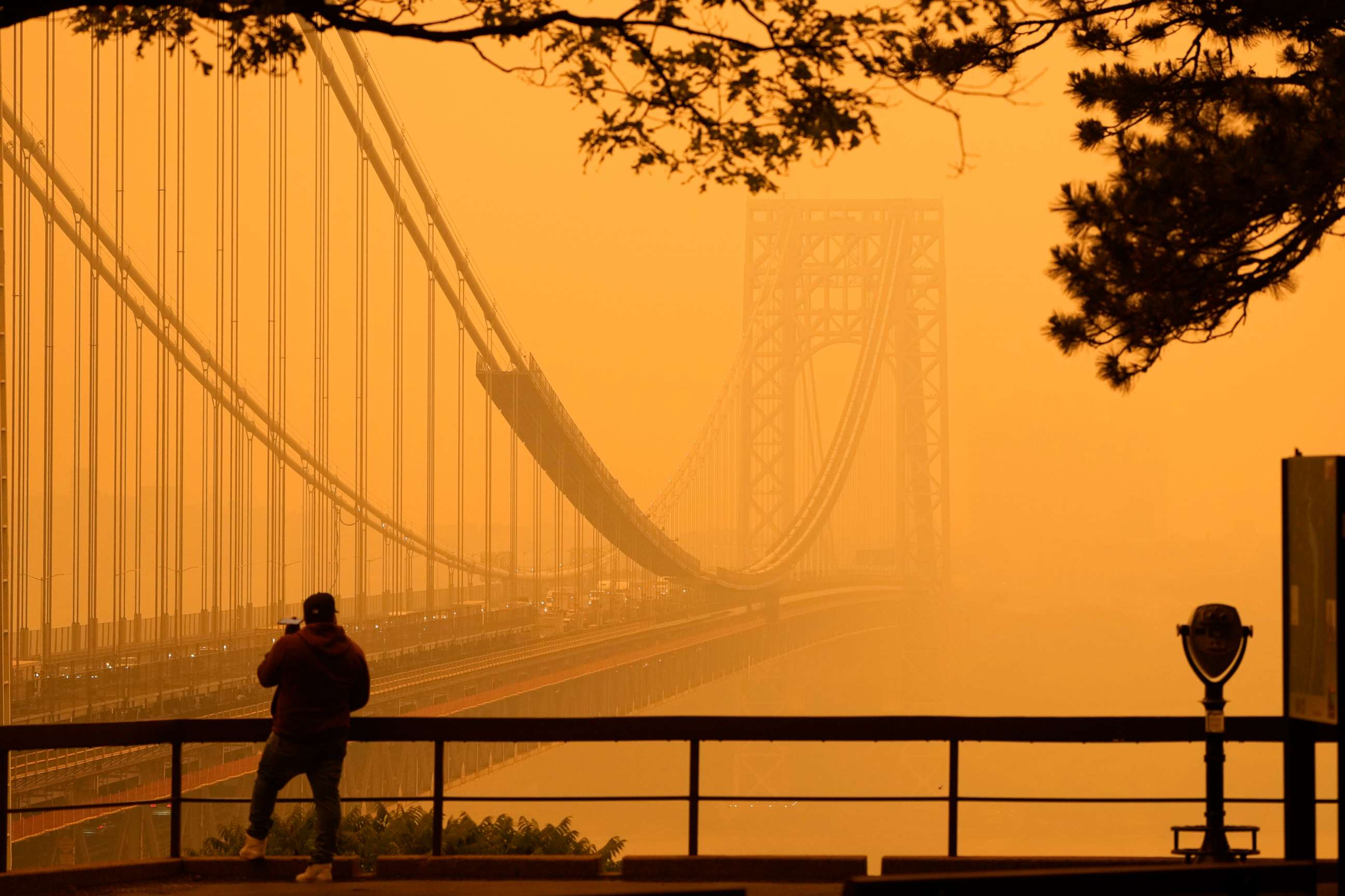 PHOTO: A man talks on his phone as he looks through the haze at the George Washington Bridge from Englewood Cliffs, N.J., June 7, 2023.