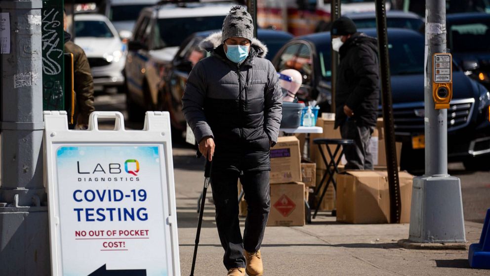 PHOTO: A person wearing a face mask walks past a COVID-19 testing sign in Queens, N.Y., March 8, 2021.