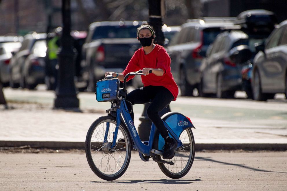 PHOTO: A woman rides a Citi Bike  while wearing a mask at Grand Army Plaza in Brooklyn, N.Y., March 9, 2021.