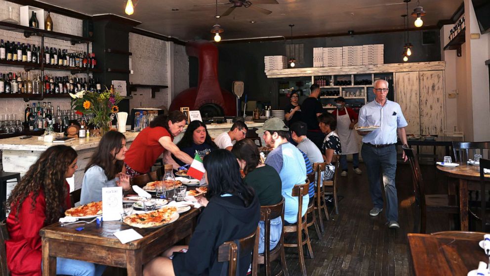 PHOTO: People enjoy pizza at a restaurant, July 27, 2021, in the Brooklyn borough of New York City.