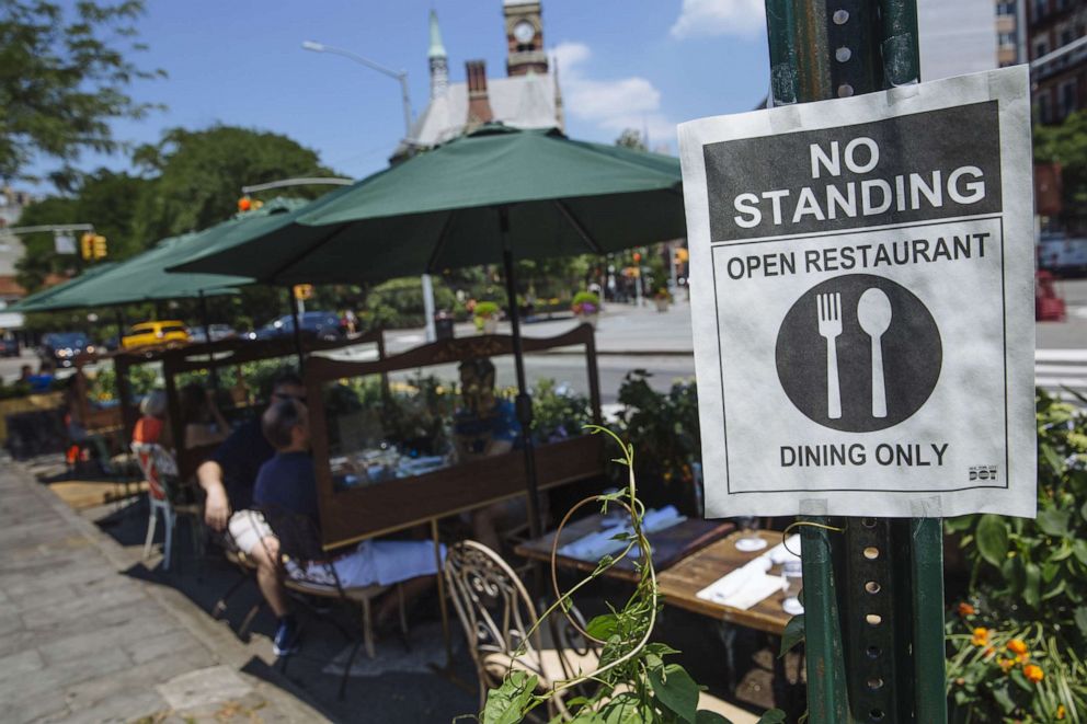 PHOTO: A "No Standing sign is displayed near tables outside of a restaurant in New York, U.S., on Monday, July 6, 2020.