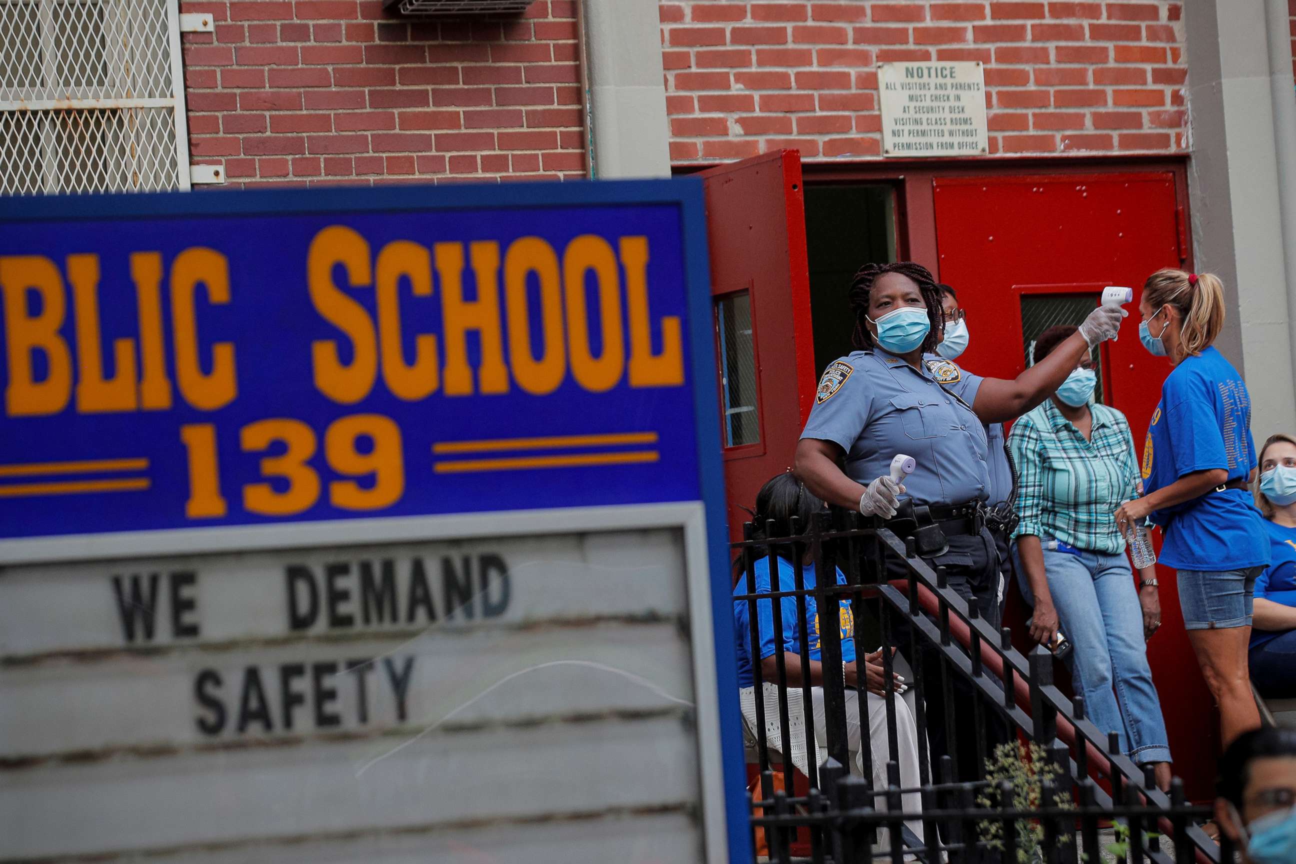 PHOTO: School Safety Officers check a teacher's temperature for safety reasons outside a school building, as preparations begin for the delayed start of the school year in Brooklyn, New York, Sept. 14, 2020.