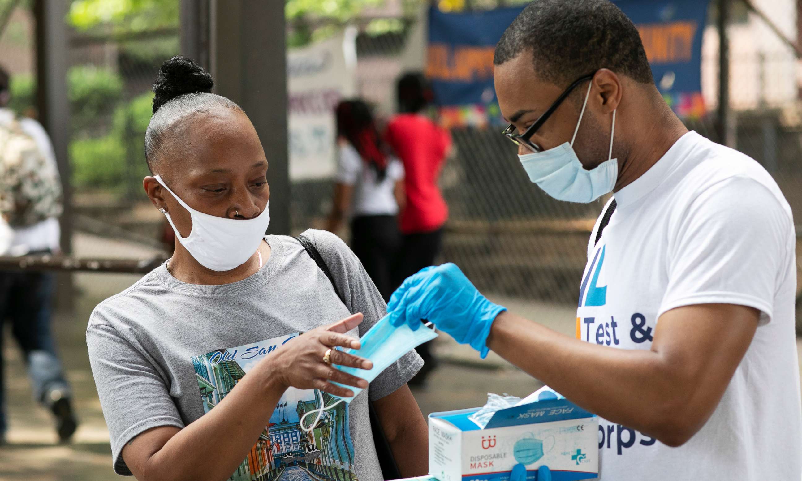 PHOTO: Stephane Labossiere, right, with the Mayor's Office of Immigrant Affairs, hands out masks and printed information about free COVID-19 testing in Brooklyn being offered by NYC Health + Hospitals, Wednesday, July 8, 2020, in New York.