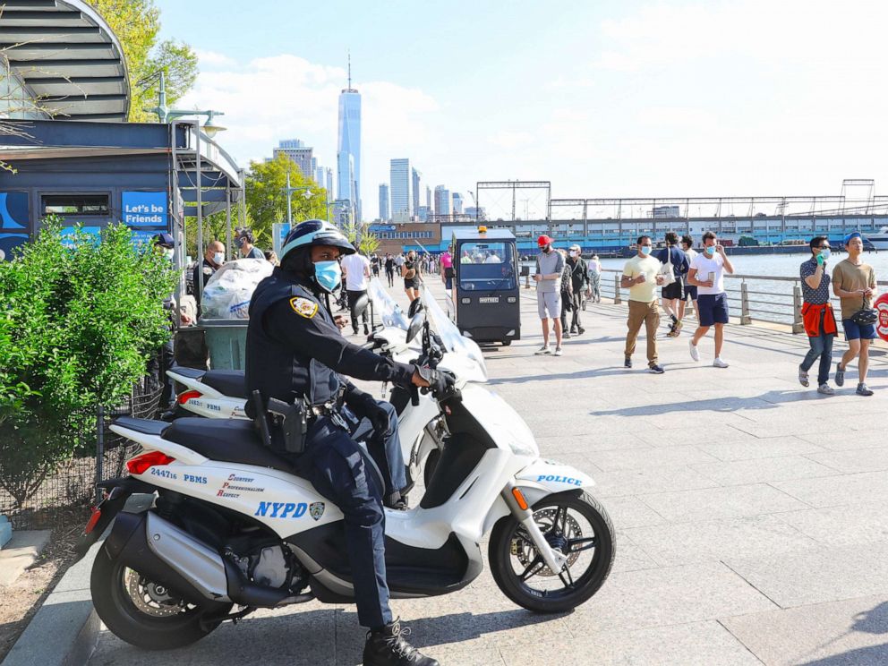PHOTO: An NYPD officer watches as people walk along the Hudson River on May 03, 2020, in New York.