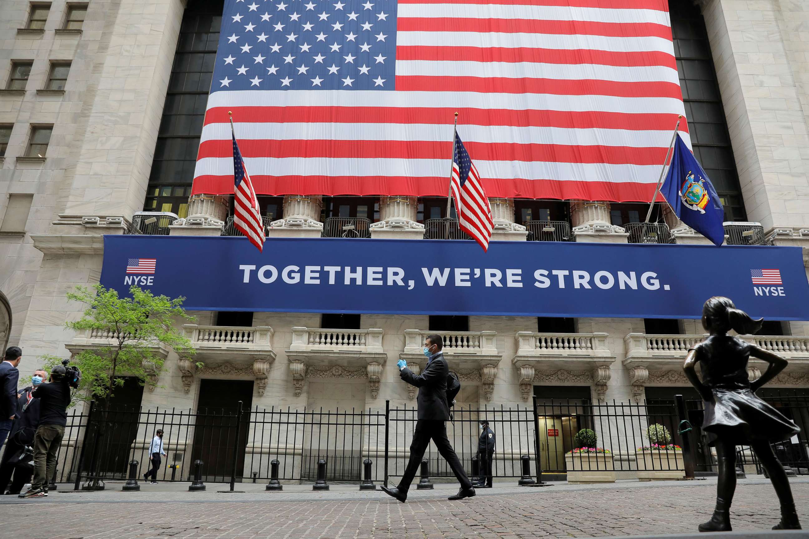 PHOTO: Pedestrians walk past the New York Stock Exchange as the building opens for the first time since March while the outbreak of the coronavirus disease (COVID19) continues in the Manhattan borough of New York, May 26, 2020.