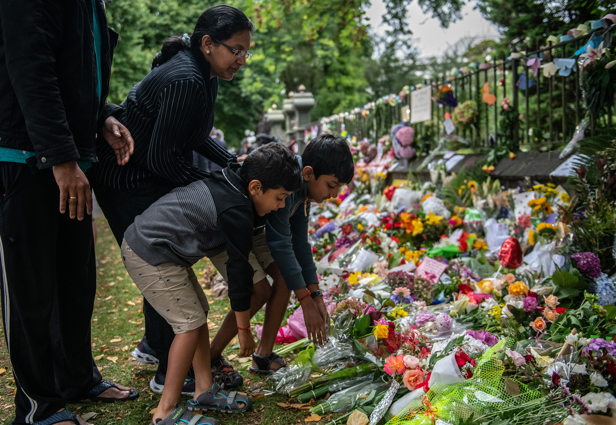 PHOTO: A family lay flowers by the wall of the Botanic Gardens, March 17, 2019 , in Christchurch, New Zealand after a mass shooting at two mosques. 