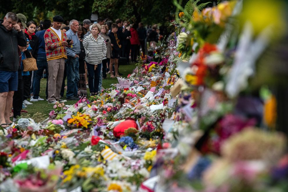 PHOTO: A family lay flowers by the wall of the Botanic Gardens, March 17, 2019 , in Christchurch, New Zealand after a mass shooting at two mosques. 