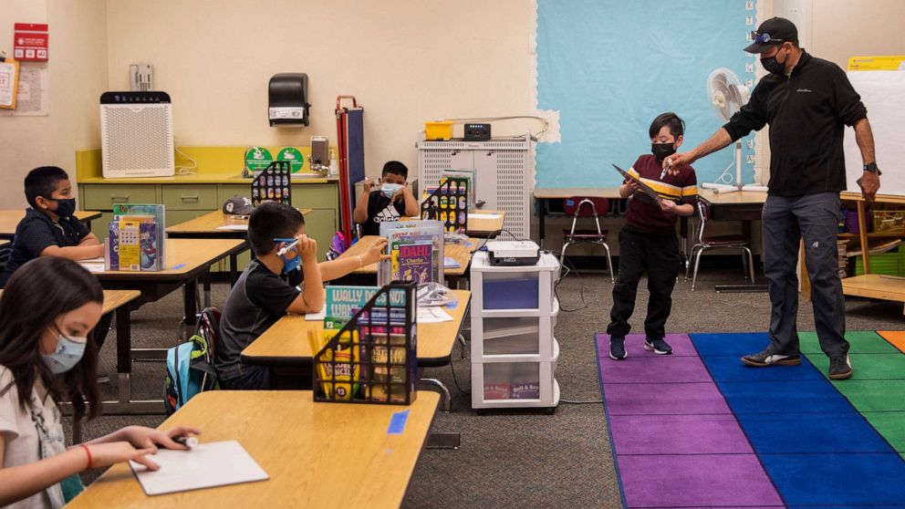 PHOTO: In this March 30, 2021, file photo, a teacher helps a student with a math problem while he teaches second grade at Garfield Elementary School in Oakland, Calif.