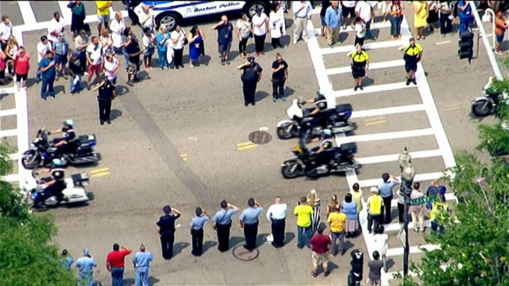PHOTO: An image made from aerial video shows people lining the roadway, waiting for the vehicle carrying the remains of Police Officer Michael Chesna en route to a funeral home in Boston, July 16, 2018.