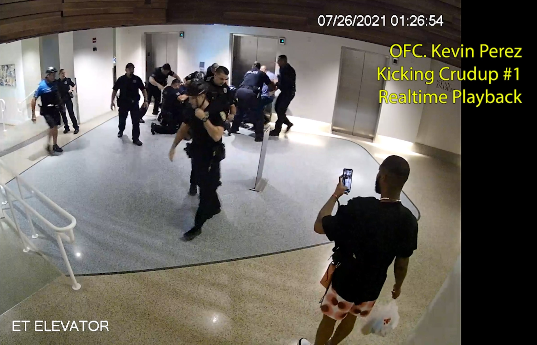 PHOTO: Officer Kevin Perez is seen as he motions to kick Dalonta Crudup while Khalid Vaughn stands on the far right recording video with his phone, in an image taken from hotel surveillance video released by the Miami-Dade State Attorney’s Office.