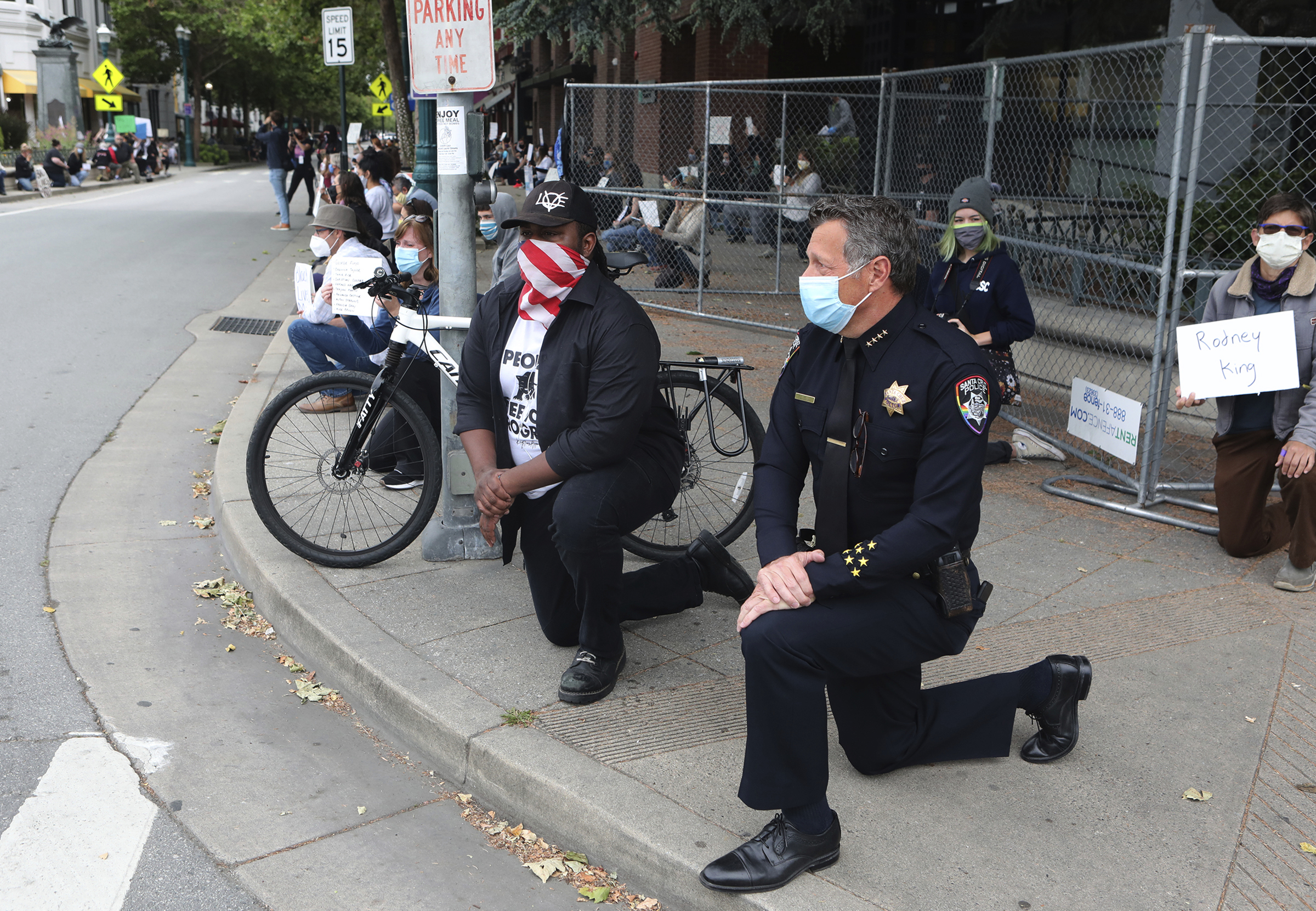 PHOTO: Santa Cruz, Calif., Police Chief Andy Mills, right, and Santa Cruz Mayor Justin Cummings, center, take a knee along with hundreds gathered on Pacific Avenue in downtown Santa Cruz, May 30, 2020.