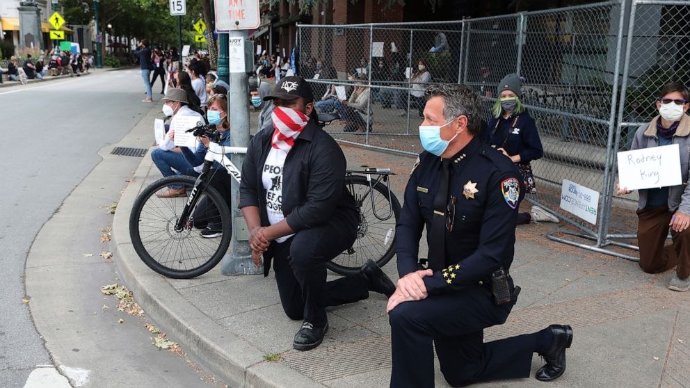 PHOTO: Santa Cruz, Calif., Police Chief Andy Mills, right, and Santa Cruz Mayor Justin Cummings, center, take a knee along with hundreds gathered on Pacific Avenue in downtown Santa Cruz, May 30, 2020.