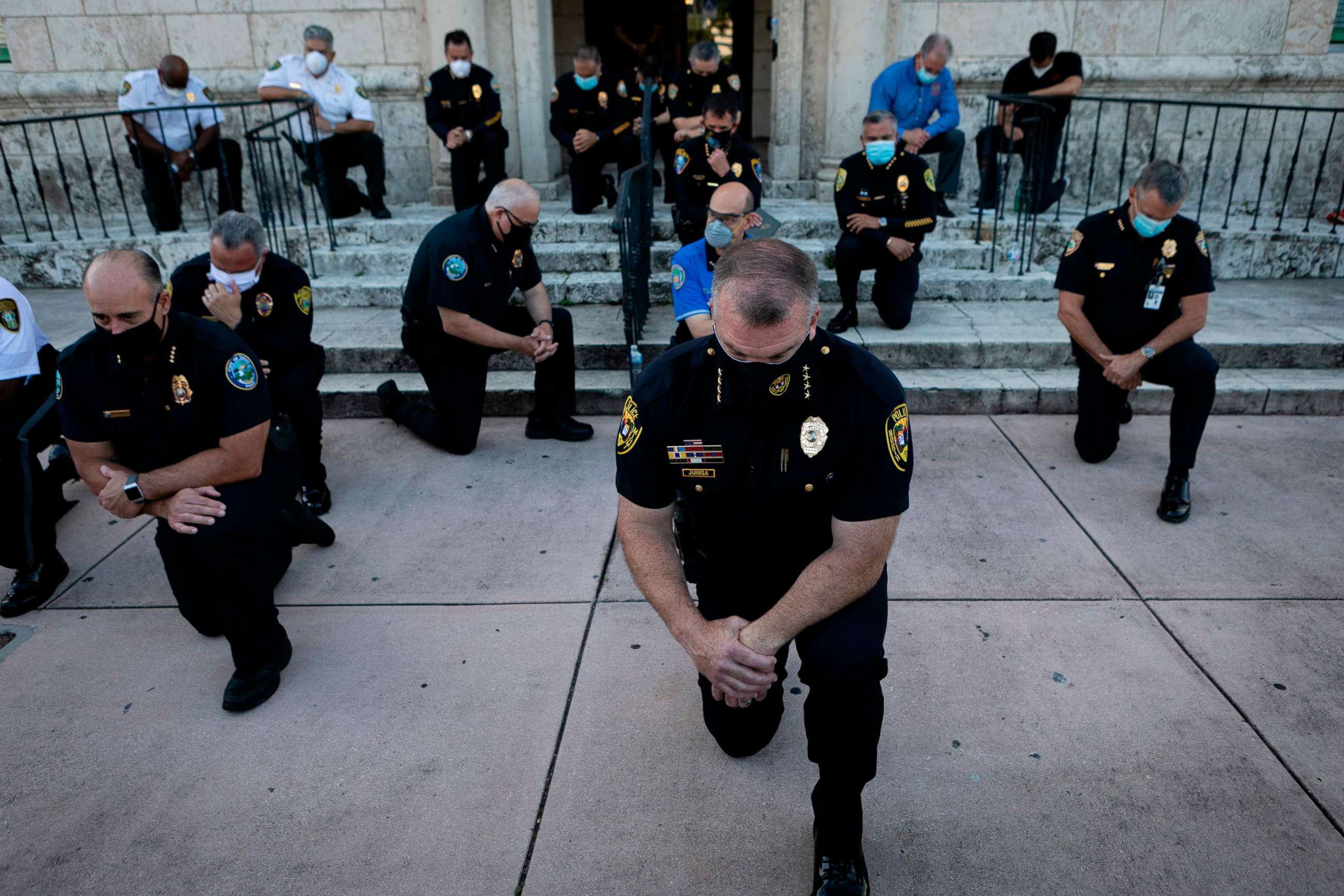 PHOTO: Police officers kneel during a rally in Coral Gables, Florida, May 30, 2020, in response to the recent death of George Floyd, an unarmed black man who died while being arrested and pinned to the ground by a Minneapolis police officer.