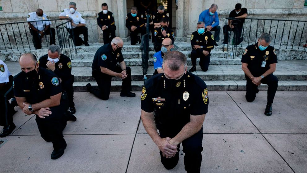 PHOTO: Police officers kneel during a rally in Coral Gables, Florida, May 30, 2020, in response to the recent death of George Floyd, an unarmed black man who died while being arrested and pinned to the ground by a Minneapolis police officer.