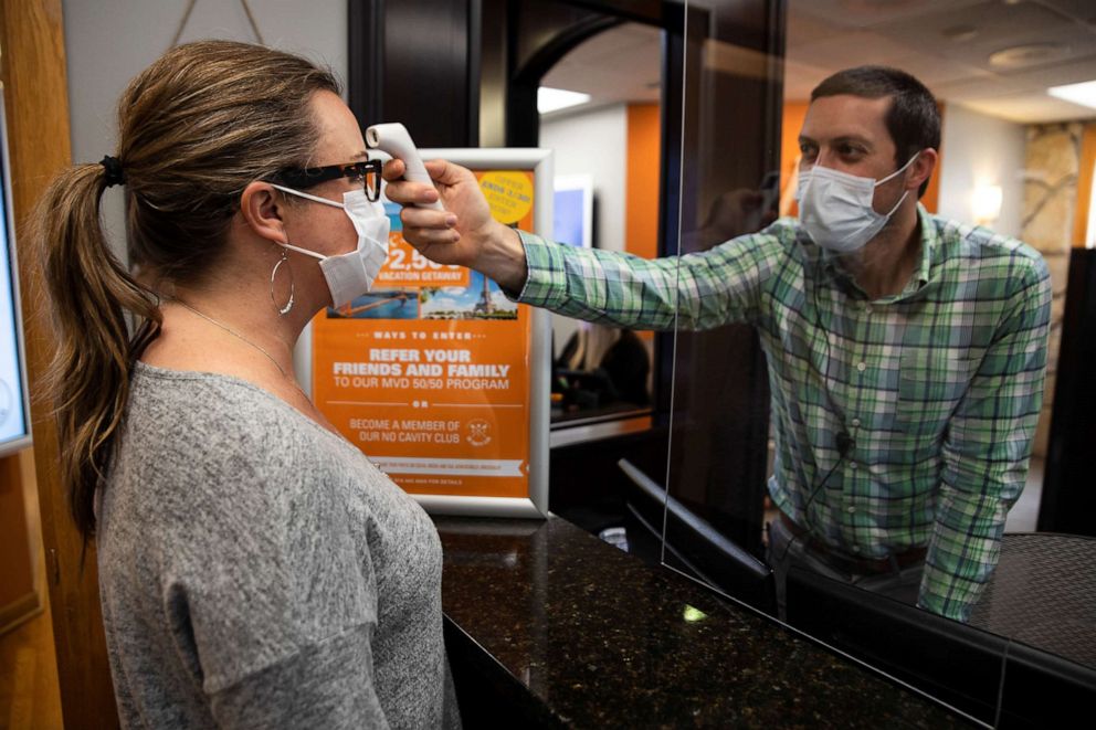 PHOTO: A dentist office manager takes the temperature of a woman as Ohio implements phase one of reopening dentists, veterinarians and elective surgeries, following the outbreak of coronavirus (COVID-19), in Columbus, Ohio, May 01, 2020.