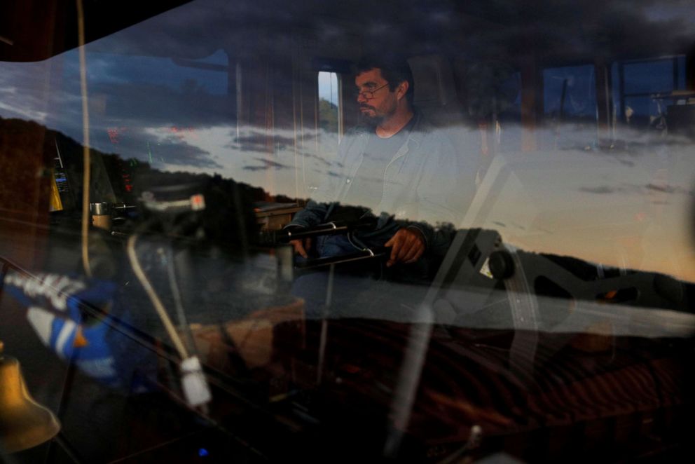 PHOTO: The Ohio River is reflected in the wheelhouse window as forty-six year-old Captain Joe Gray pilots Campbell Transportation Company's towboat MK McNally pushing 15 barges near Ironton, Ohio, Sept. 12, 2017.