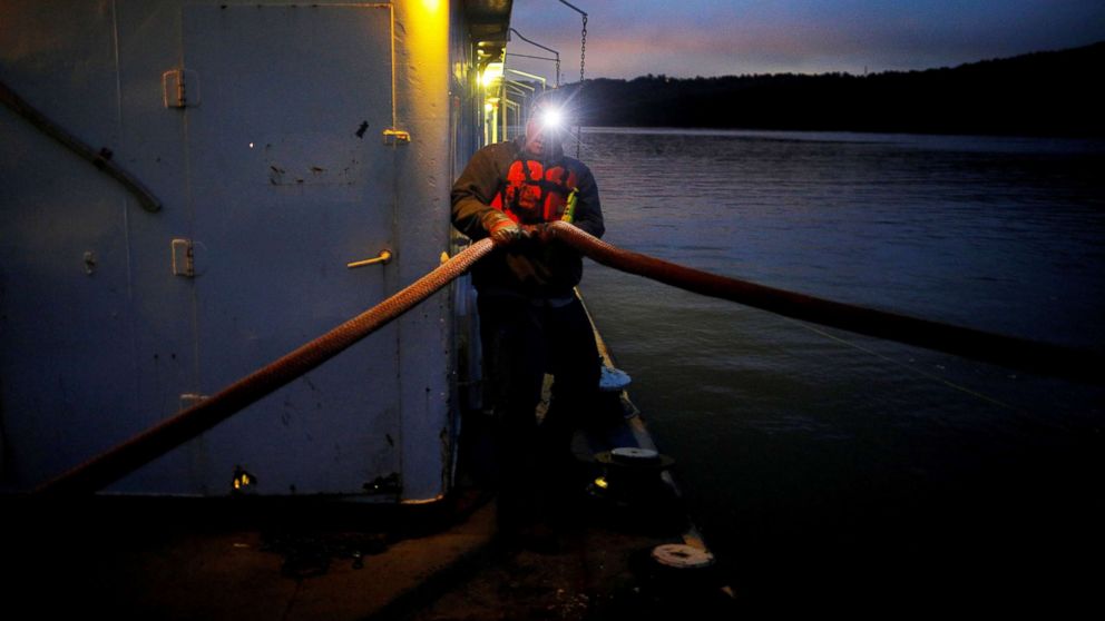 Twenty-one year-old deckhand trainee Jacob Bumgarner holds a line while wearing a headlamp shortly before sunrise on Campbell Transportation Company's towboat MK McNally on the Ohio River near, Cincinnati, Ohio, Sept. 14, 2017. 
