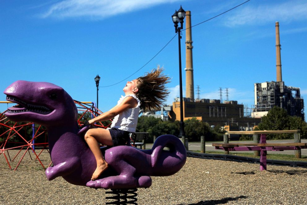 PHOTO: Eight year-old Shalynn Billingsley rides a dinosaur in a playground in Racine, Ohio, Sept. 24, 2017. The playground is on the banks of the Ohio River and across from the retired AEP Philip Sporn Power Plant in Letart, W.Va. 