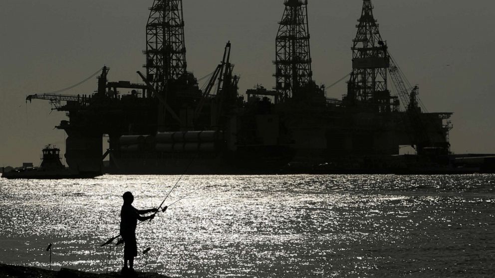 PHOTO: A man fishes near docked oil drilling platforms in Port Arkansas, Texas,  May 8, 2020.