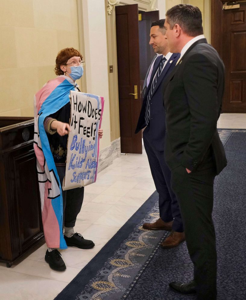 PHOTO: In this March 30, 2022, file photo, Kara Klever wears what appears to be a transgender flag while holding a sign protesting Governor Kevin Stitt's signing of the bill SB2, the Save Women in Sports Act, at the Capitol, on Oklahoma City. 