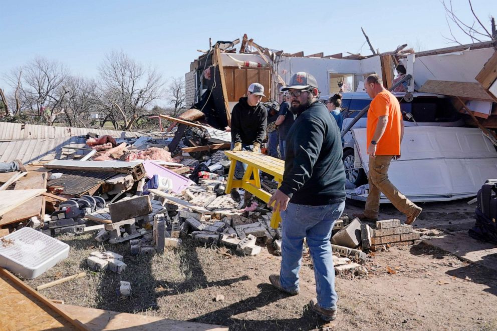 PHOTO: Adam Lee, left, and Jr. Ibarra, right, carry a table from a friend's home after it was destroyed by a tornado, Dec. 13, 2022, in Wayne, Okla.