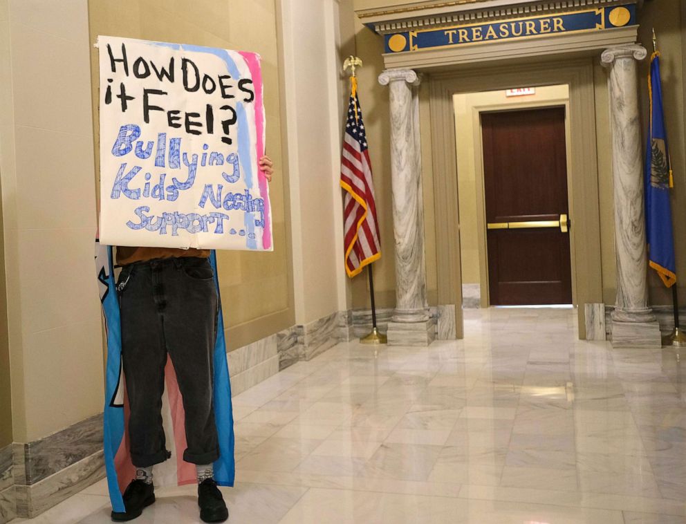 PHOTO: Kara Klever holds a sign in protest, March 30, 2022, of Governor Kevin Stitt signing SB2, the Save Women in Sports Act, in the Blue Room at the Capitol in Oklahoma City, Oklahoma.