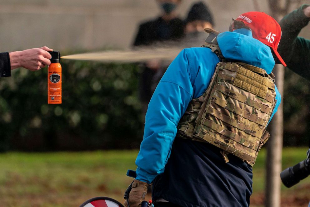 PHOTO: A counterprotester sprays a Donald Trump supporter with bear mace during a rally on Dec. 12, 2020 in Olympia, Wash.