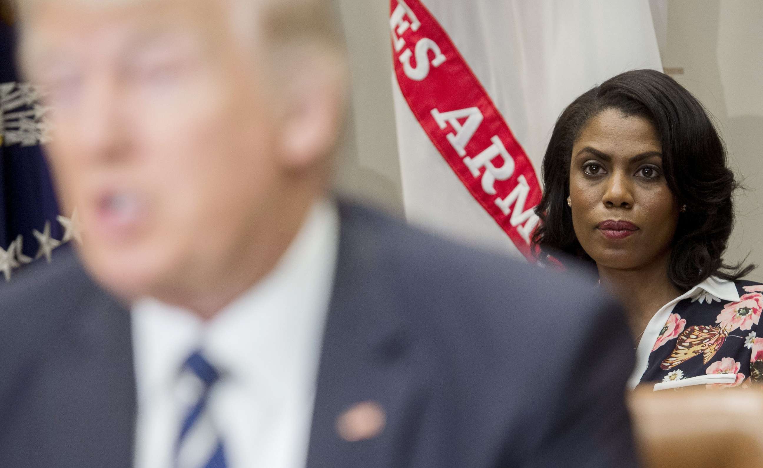 PHOTO: Omarosa Manigault (R), White House Director of Communications for the Office of Public Liaison, sits behind US President Donald Trump as he speaks during a meeting in the Roosevelt Room of the White House, Feb. 14, 2017.