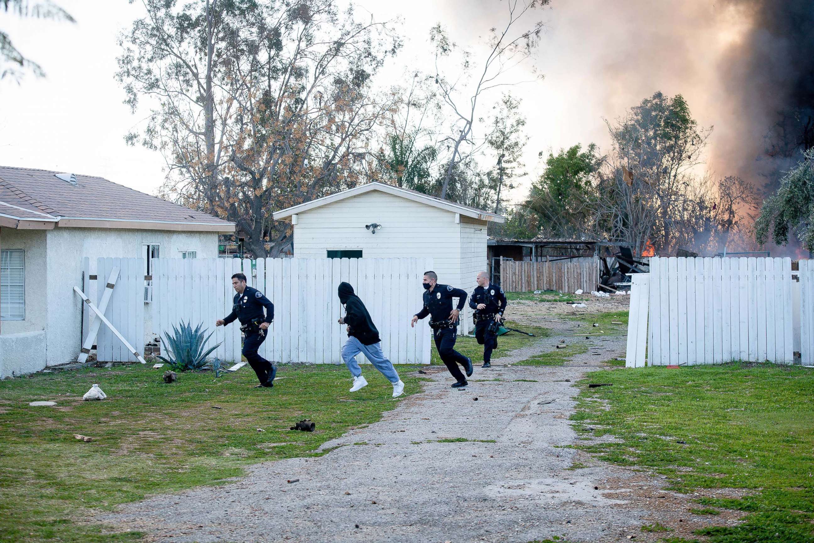 PHOTO: Ontario Police officers and a man are seen running away from an explosion at a home in Ontario, Calif., March 16, 2021. 