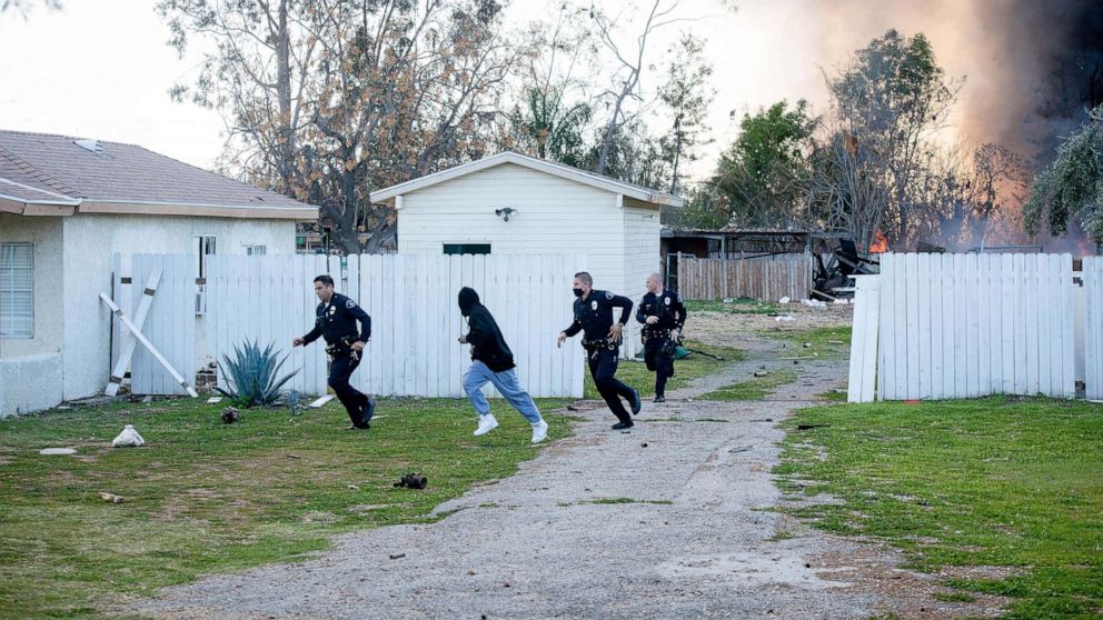 PHOTO: Ontario Police officers and a man are seen running away from an explosion at a home in Ontario, Calif., March 16, 2021. 
