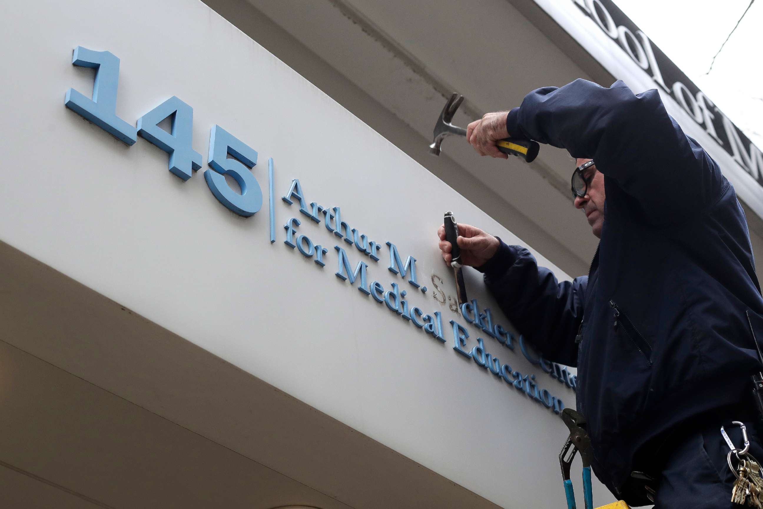 PHOTO: Worker Gabe Ryan removes a sign that includes the name Arthur M. Sackler at an entrance to Tufts School of Medicine, Dec. 5, 2019, in Boston.