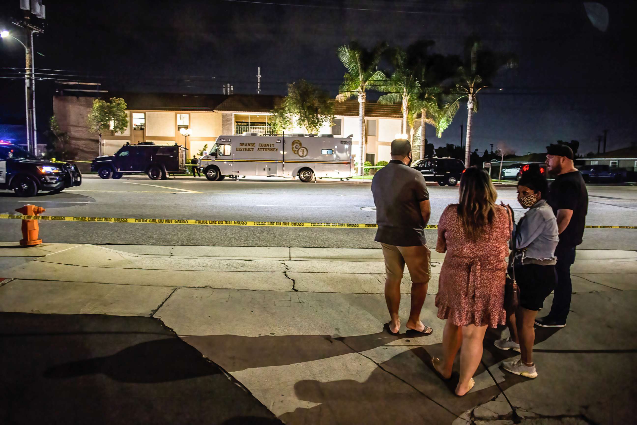 PHOTO: Locals stand and wait for updates across the street from the scene of the fatal shootings of four people, including a child, in Orange, Calif., March 31, 2021.