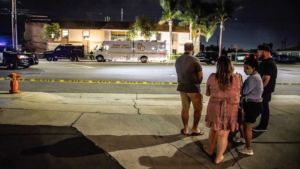 PHOTO: Locals stand and wait for updates across the street from the scene of the fatal shootings of four people, including a child, in Orange, Calif., March 31, 2021.