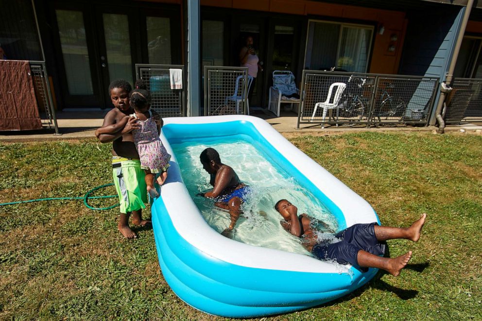PHOTO: Jalen Askari, 7, right, plugs his nose as he falls into the pool he is playing in with his siblings, from left, Amari, 5, Bella, 2, and DJ, 10, in Portland, Ore., July 26, 2022.