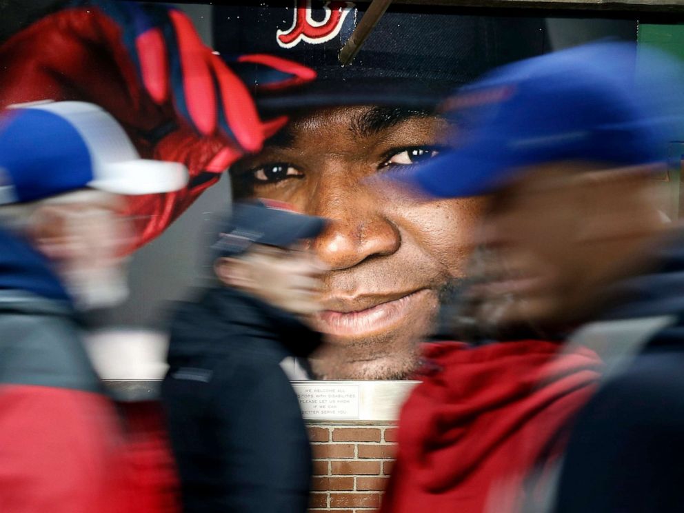 PHOTO: Fans walk past a picture of David Ortiz of the Boston Red Sox before a baseball game at Fenway Park in Boston on October 1, 2016.