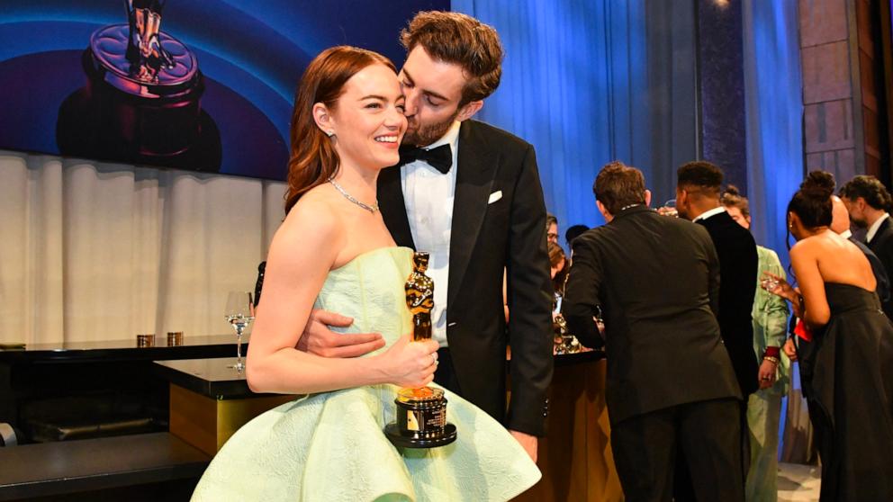 PHOTO: Emma Stone gets a kiss from husband Dave McCary as she holds her Oscar for Best Actress in a Leading Role while attending the 96th Annual Academy Awards Governors Ball, in Hollywood, Mar. 10, 2024.