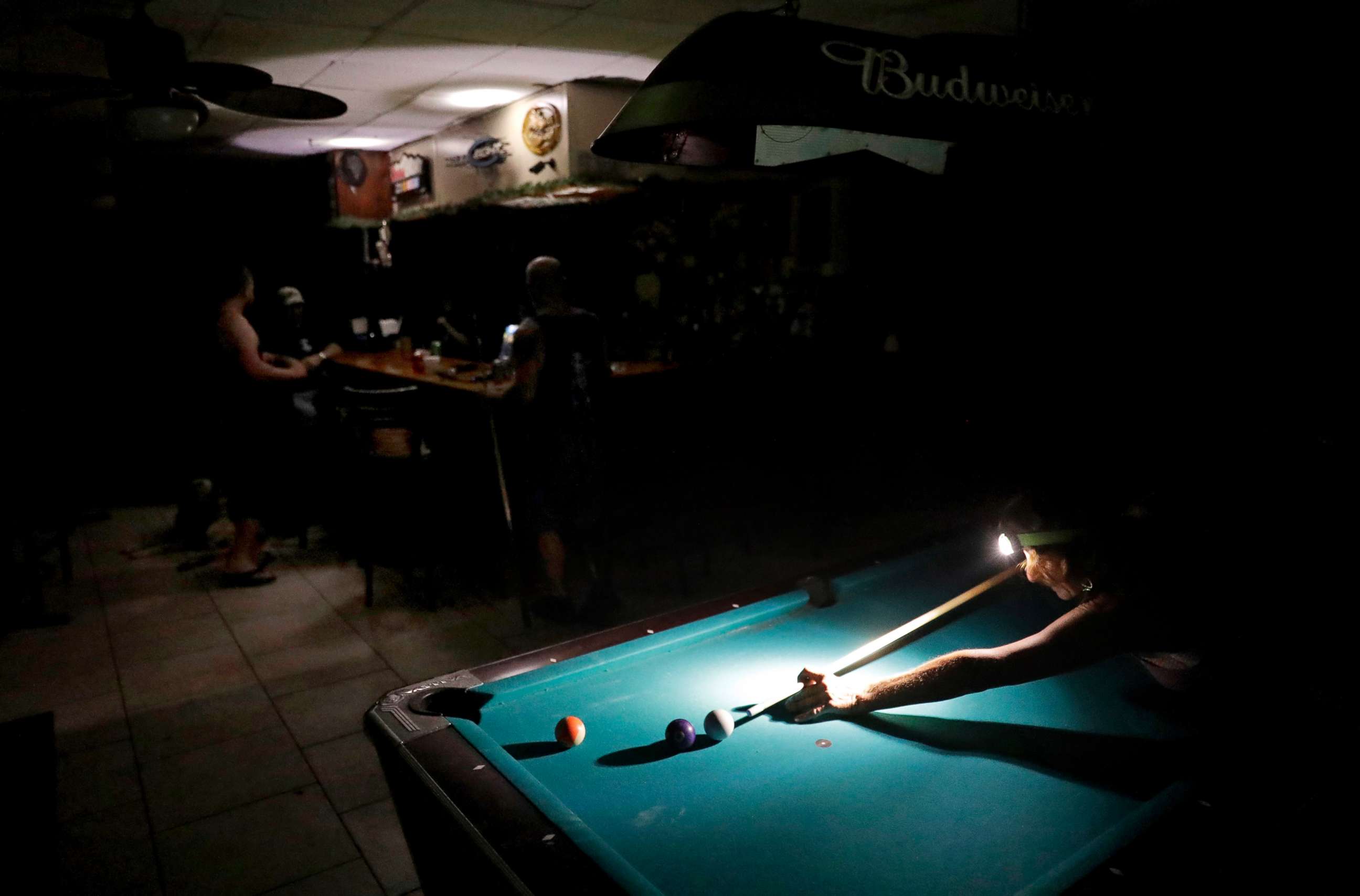 PHOTO: Lisa Borruso plays pool using a headlamp as the power remains out following Hurricane Irma at Gators' Crossroads in Naples, Fla., Sept. 11, 2017. 
