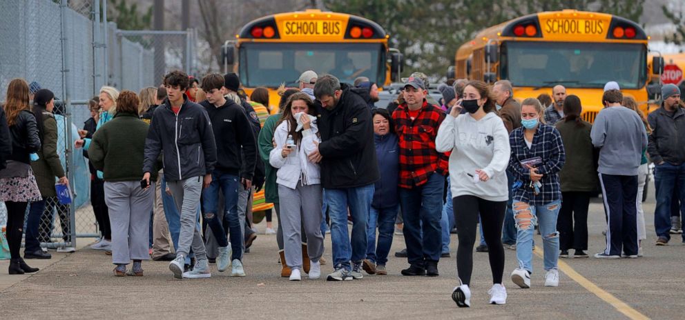 PHOTO: Parents walk away with their kids from the Meijer's parking lot in Oxford where many students gathered following an active shooter situation at Oxford High School in Oxford, Mich., Nov. 30, 2021.