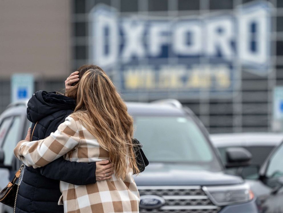 PHOTO: People comfort each other while visiting a memorial being built at an entrance to Oxford High School following an active shooting incident, Dec. 1, 2021.