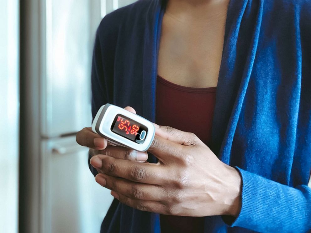 PHOTO: Close-up of woman using pulse oximeter to measure blood oxygen saturation level and heart rate.