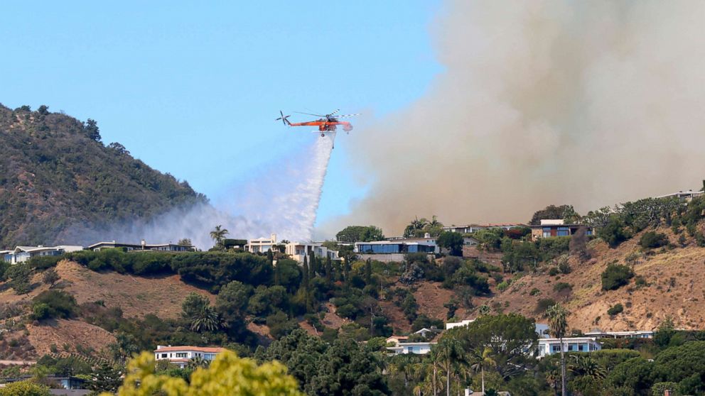 PHOTO: A helicopter makes a water drop as flames threaten homes on a ridgeline in the Pacific Palisades area of Los Angeles, Oct. 21, 2019.