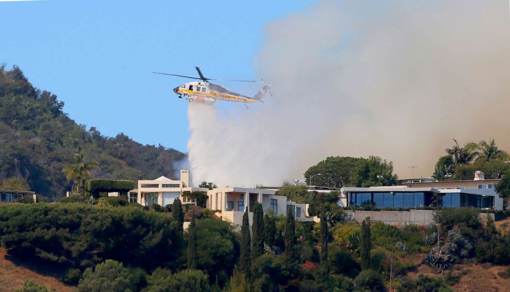 PHOTO: A helicopter makes a water drop as flames threaten homes on a ridgeline as a wildfire threatens homes in the Pacific Palisades area of Los Angeles, Oct. 21, 2019.