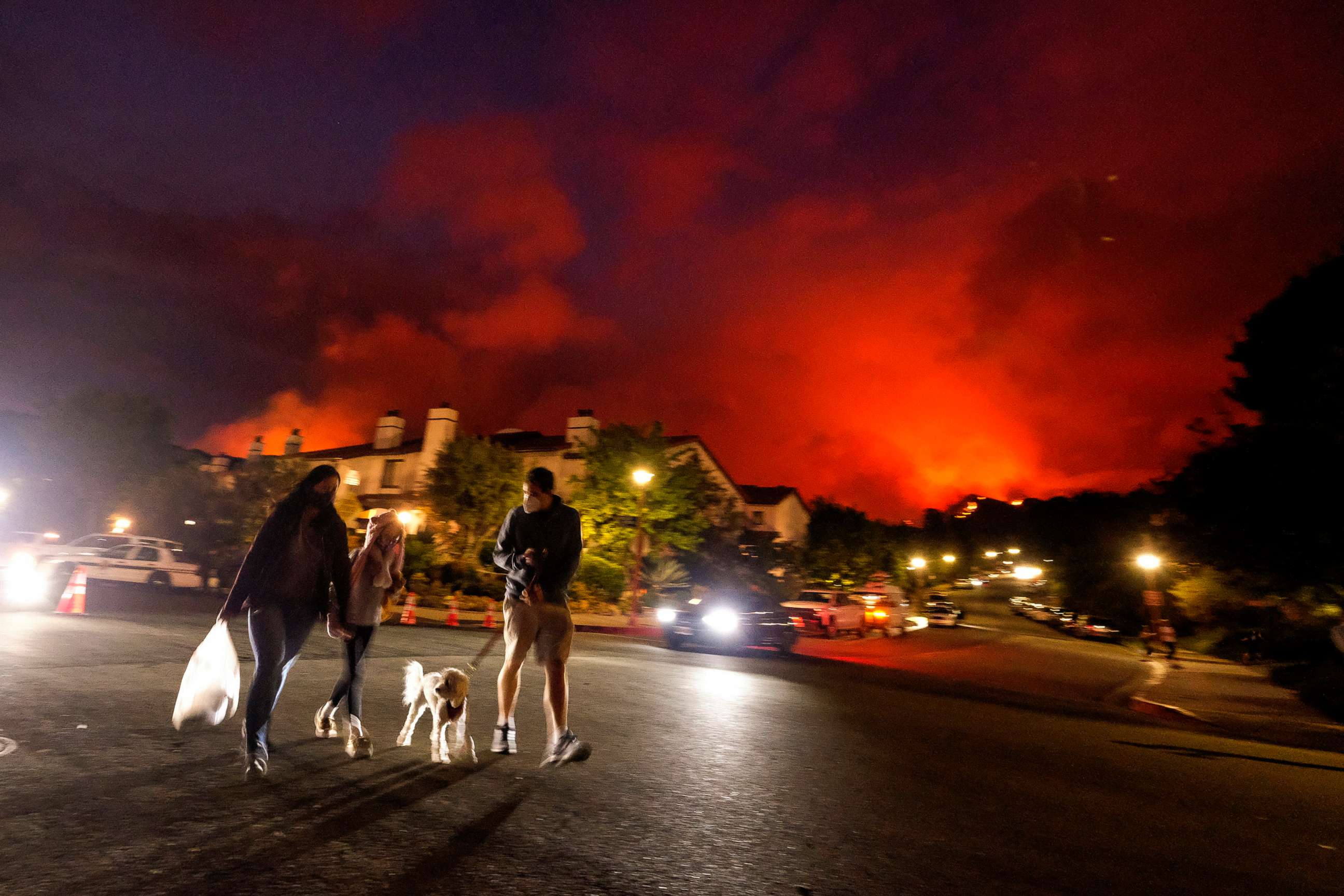 PHOTO: Residents walk past as a brush fire burns behind homes in the Pacific Palisades area of Los Angeles on May 15, 2021.