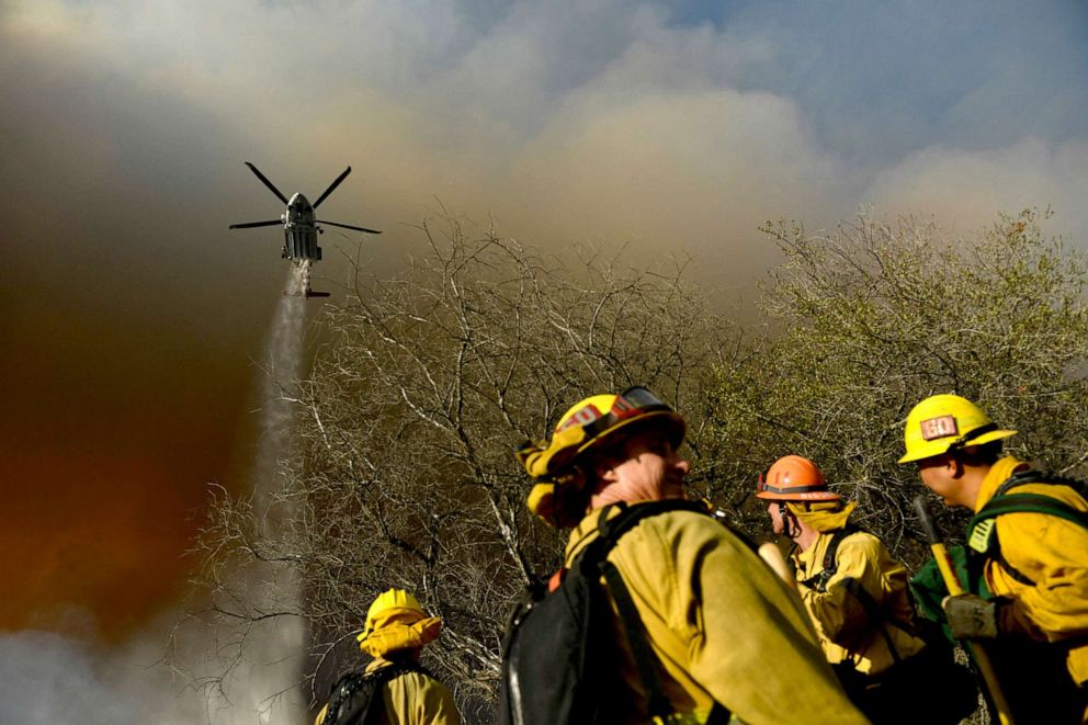 PHOTO: Firefighters keep a lookout as a Los Angeles Fire Department helicopter makes a water drop on the Palisades fire in Topanga State Park in Los Angeles, May 15, 2021.